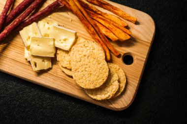 Çerezli ahşap servis tahtası. Sosis, suluguni peyniri, koyu arkaplanda yakın plan peyniri. sağlıklı organik gıda