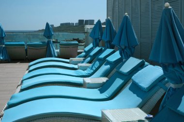 Otelin havuzunun yanındaki terasta güneşleniyorlar. Denizde yaz tatili. Boş güneş pansiyonları