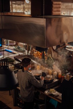 Şef, restoranın üst katında, mutfakta bir Asya yemeği hazırlıyor. Asya Kafesi