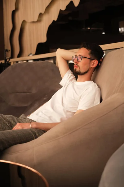 Homem Com Uma Shirt Branca Está Descansando Uma Poltrona Grande — Fotografia de Stock