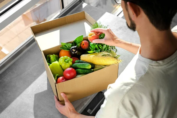 man ordered food delivery to his home. a man unpacks an online order of vegetables and fruits from an online store. fast delivery of fresh products. Food for vegetarian and vegan