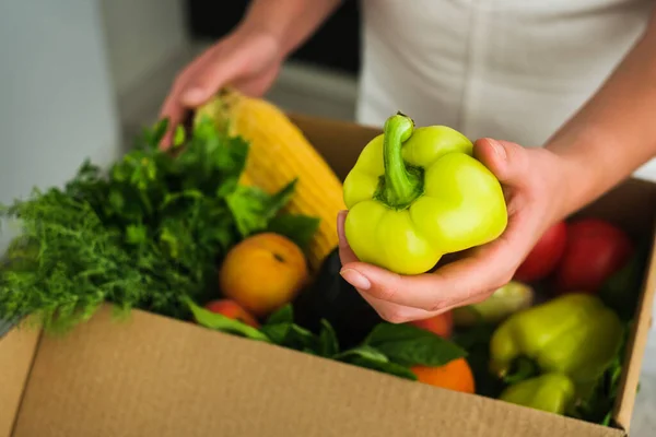 a girl unpacks a parcel from a store with vegetables and fruits. online delivery of goods to your home. vegetables in a box close-up