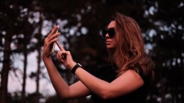 Güzel bir kadın telefondaki videoyu inceliyor. blog yazarı içeriği vuruyor