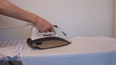 Beyaz arka planda buharlı ütülü beyaz tişört giyen bir adam.