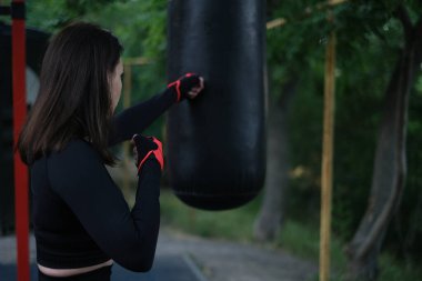 Genç bayan sporcu esmer boks, güneşli bir yaz gününde açık hava spor sahasında.