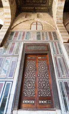 Tarihi süslenmiş ahşap kapılı eski bir mermer duvar.