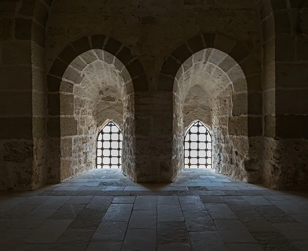 Un muro di pietra con due finestre retroilluminate adiacenti con griglia in acciaio a — Foto Stock