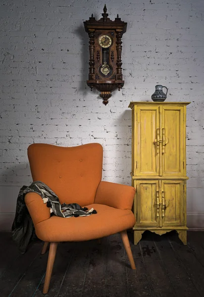 Sillón naranja vintage, armario amarillo, reloj de péndulo y bufanda negra — Foto de Stock