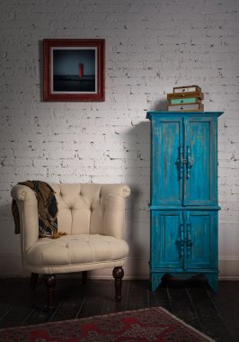 Klasik bej koltuk, mavi vintage dolap, eşarp ve paintin