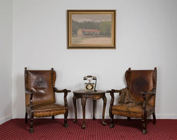 Два деревянных кресла, небольшой журнальный столик и старый телефон — стоковое фото