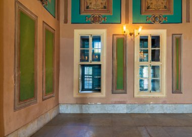 Yeşil panjurlu ahşap pencereler, süslü kenarlı yeşil çerçeveler ve fayanslı mermer zemin.