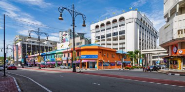 Bandar Seri Begawan, Brunei - Feb. 24, 2025: Alan Sultan street featuring colorful shophouses and the Yayasan Sultan Haji Hassanal Bolkiah Complex. Cars and people on Jalan Sultan under a blue sky