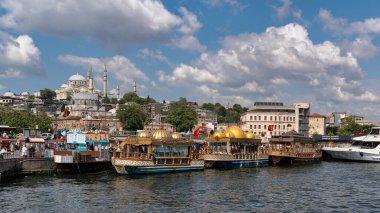 İstanbul, Türkiye - 14 Haziran 2025: Eminonu 'daki Golden Horn' a demirli balık sandviçleri satan geleneksel altın kubbeli tekneler, arka planda ise Süleyman Camii bulunuyor. Mavi gökyüzüyle güneşli bir gün