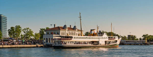 İstanbul, Türkiye - 14 Haziran 2025: Kadıköy Iskele 'den kalkan yolcu feribotu. Tarihi feribot terminali ve hareketli rıhtım güvertesindeki insanlar.