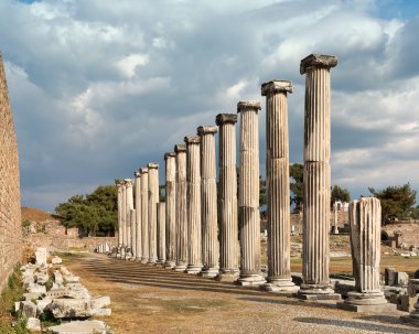 Antik Roma sütunları Asklepion, Pergamon, Bergama, Türkiye 'de kutsal yol üzerindedir. Tarihi kalıntılar dramatik bulutlu bir gökyüzünün altında antik mimari mirası sergiliyor..
