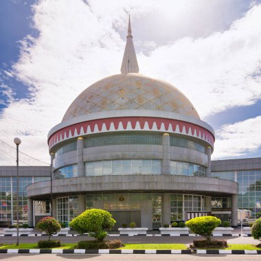 Royal Regalia Müzesi, Bandar Seri Begawan, Brunei Darussalam 'da bulutlu bir gökyüzünün altında altın desenli kubbesi ve kubbesi olan modern bir bina.