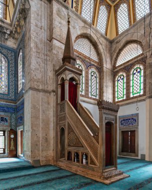 Muradiye Camii, Manisa, Türkiye 'de süslü ahşap minibarı, mavi desenli halısı ve karmaşık İslami kaligrafisi olan canlı vitray pencereleri sergileniyor.