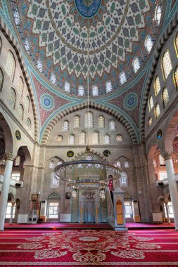 Burunguz Camii iç mimarisi, Kayseri, Türkiye. Süslü bir kubbe, canlı bir vitray ve zengin desenli kırmızı halı ile çarpıcı bir İslami mimari.