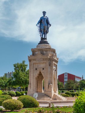 Türkiye 'nin Konya kentindeki Atatürk Anıtı. Mustafa Kemal Atatürk 'ün askeri üniformalı bronz heykeli, elinde buğday ve kılıç, mavi gökyüzünün altındaki yeşil bahçelerin arasındaki süslü taş bir kaidede.