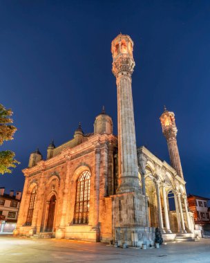 Türkiye 'nin Konya kentindeki Majestic Osmanlı Barok Aziziye Camii gece aydınlandı. Süslü taş cephesi ve iki yüksek minare soluk yıldızlı derin mavi gökyüzüne karşı duruyor.