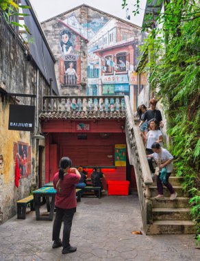 Kuala Lumpur, Malezya - 21 Şubat 2025 Kwai Chai Hong Heritage Yolu. Eski binalarda canlı duvar resimleri, merdivenlerde insanlar ve açık havada oturma yerleri olan tarihi bir ara sokak. Eğreltiotları duvarları süslüyor.