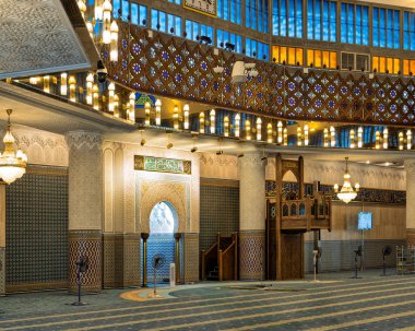 Kuala Lumpur, Malezya 'daki Mescid Negara Ulusal Camii dua salonunun içidir. Karmaşık İslami mimari, avizeler, mavi ve turuncu renkli camlar, desenli halılar.
