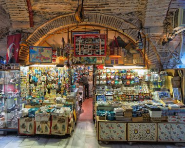 İzmir, Türkiye - 31 Mart 2025: Kizlaragasi Han Çarşısı 'nda canlı hediyelik eşya dükkanı, Türk el sanatları, nazar, nazar, seramik ve kemerli tavan altında bayraklar sergileniyor