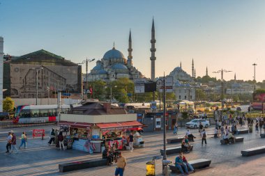 İstanbul, Türkiye - 5 Haziran 2025: Yeni Cami ve Süleyman Camii, gün batımında yayalar, tramvaylar ve sokak satıcılarıyla dolu Eminonu Meydanı 'na göz yumdu