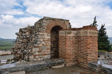Gökyüzü bulutlu, yeşil bir vadiye bakan Ayasuluk Şatosu, Selcuk, İzmir, Türkiye 'de antik taş ve tuğla kemer yolu