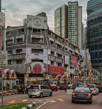 Kuala Lumpur, Malezya - 28 Şubat 2025: Mangala Theebam mağazası, süslenmiş kemerler, trafik ve bulutlu gökdelenler ile küçük Hindistan Brickfield caddesi manzarası