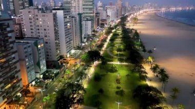 Sao Paulo, Brezilya 'nın Santos kıyı şehrinde aydınlatılmış bir cadde. Sahilde gün batımının şehri. Brezilya, Sao Paulo 'daki Santos sahil şehrinde aydınlatılmış bulvar. Sahilde günbatımının şehri. Santos sahil şehrinde aydınlatılmış bulvar. Şehir manzarası görünümü.