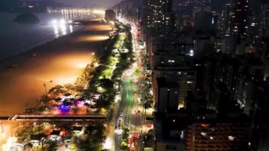 Sao Paulo, Brezilya 'nın Santos kıyı şehrinde aydınlatılmış bir cadde. Sahilde gün batımının şehri. Brezilya, Sao Paulo 'daki Santos sahil şehrinde aydınlatılmış bulvar. Sahilde günbatımının şehri. Santos sahil şehrinde aydınlatılmış bulvar. Şehir manzarası görünümü.