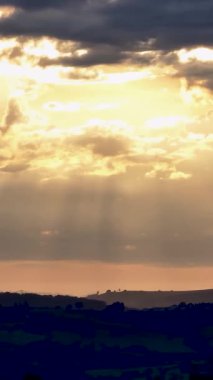 Kırsal hayat manzarasında huzurlu bir gün batımı. Kırsal kesimde gün batımı. Gün batımında bulutlar arasında güneş ışınları. Günbatımı gökyüzü manzarası. Renkli ufuk çizgisi. Renkli ufuk çizgisi. Bulutlar arasında güneş ışınları.