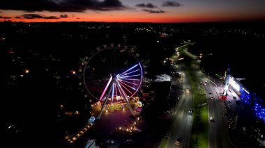 Canela Rio Grande Do Sul Brezilya 'da dönme dolap aydınlandı. İnsanların gezintilerde eğlendiği lunapark. İnşaat endüstrisi Skyline High Rise Building Awesome. Gün batımı.
