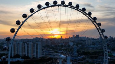 Candido Portinari Park Sao Paulo Brezilya 'da Sunset Ferris Wheel. Şehirdeki hareketli bir lunaparktaki uzun dönme dolap. Metropolitan Şirketi Binası Canlı Bina.