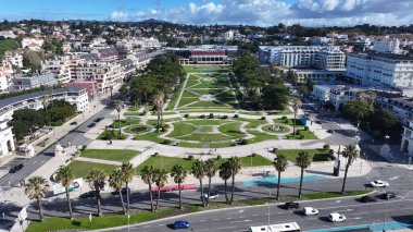 Portekiz 'in Cascais Lizbon bölgesindeki Estoril Kumarhanesi. İnsansız hava aracı, etrafı gür ağaçlarla çevrili kaldırımlı bir bahçe yakalıyor. İnşaat Manzarası Panoramik Şehir Görünümü Meşgul. Panoramik Şehir Görünümü.