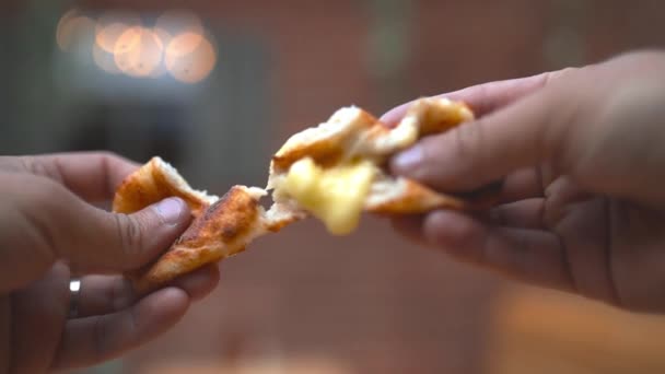 Two hands holding a cheesy dough ball broken in two spilling out its filling — Stock Video