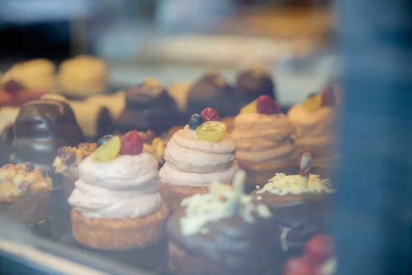 Chocolade en roommuffins en cupcakes door het raam van een bakkerij — Stockfoto