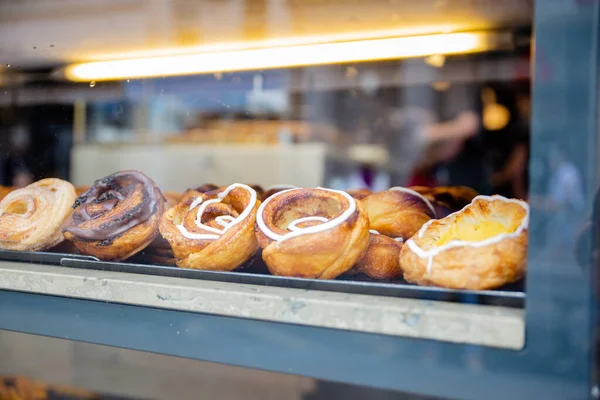 Deens gebak met chocolade en room door het raam van een bakkerij — Stockfoto