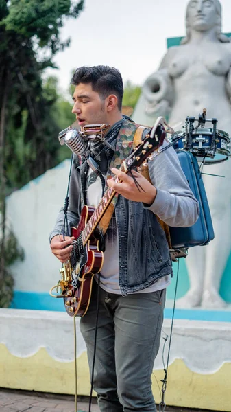 Mann spielt mehrere Instrumente gleichzeitig vor Brunnen — Stockfoto