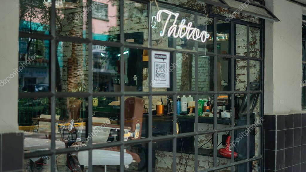 Picture of a Tattoo light sign on a large window from barber shop and tattoo studio