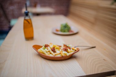 Patates kızartması, kabaklı şehriye ve ahşap masada bir tuvalet şişesi.