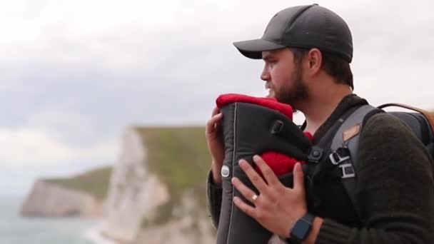 Homem com seu bebê aprecia a vista da costa jurássica — Vídeo de Stock