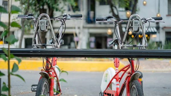 Bicicletas públicas estacionadas en la calle con un edificio borroso como fondo — Foto de Stock