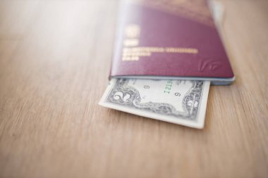 İsveç pasaportunun içinde kısmen tahta bir masa üzerinde 2 dolarlık banknot.