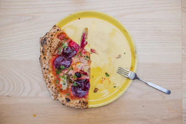 Boven het zicht van minder dan een halve dikke veganistische pizza en een vork op een gele plaat — Stockfoto