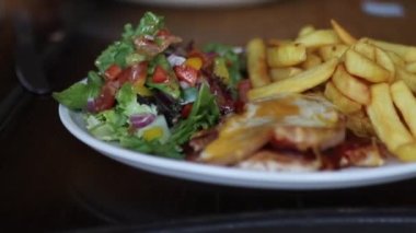 Eggs Benedict with Salad and Fries on a Wooden Table