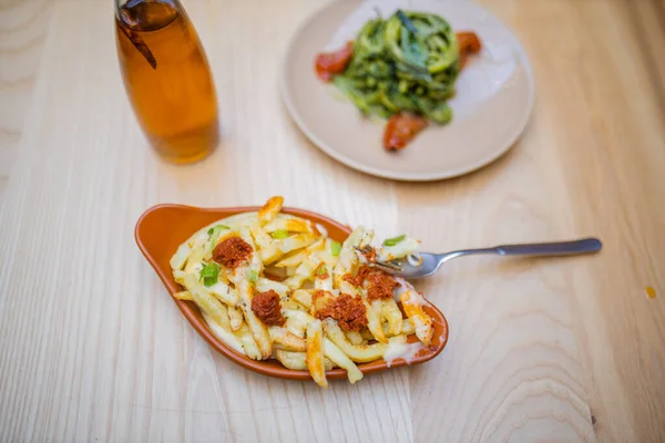 Des frites, des nouilles aux courgettes et une bouteille de vinaigrette sur une table en bois — Photo