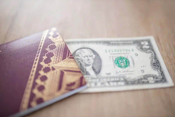 Twee Dollar Bill gedeeltelijk in een Zweeds paspoort op een houten tafel — Stockfoto