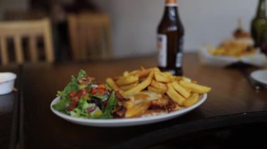 Eggs Benedict with Salad and Fries on a Wooden Table